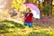 Kid with umbrella playing in autumn rain