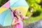 Kid with umbrella playing in summer rain.