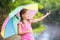 Kid with umbrella playing in summer rain.