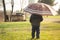 Kid in village watching playful dogs holding umbrella