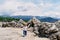 Kid walks on a stone platform with boulders against a background of mountains