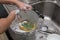 Kid washing dishware in kitchen sink with soapy sponge