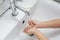 Kid washing hands in a white basin with a bar of white soap.