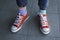 Kid wearing different pair of socks. Child legs in mismatched socks on gray background. Odd Socks day, Anti-Bullying