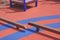 Kids Balance beams on colorful orange and blue rubber floor in public outdoors playground area