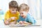 Kids brothers practice read together looking at book laying on the floor