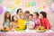 Kids celebrate birthday party and blow candles on festive cake