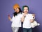 Kids in colorful hats asian girl and caucasian boy with his polar bear toy posing eating lollipop candy on purple
