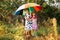 Kids with colorful umbrella playing in autumn shower rain. Little girls play in park by rainy weather.