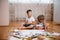 Kids drawing on floor on paper. Preschool boy and girl play on floor with educational toys - blocks, train, railroad, plane. Toys