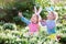 Kids on Easter egg hunt in blooming spring garden