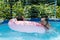 Kids enjoy swimming and floating in leisure pool during summer vacation, fun