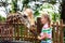 Kids feed giraffe at zoo. Children at safari park.