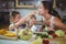 Kids feeding a slice of yellow bell pepper to mother in kitchen