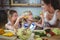 Kids feeding a slice of zucchini to mother in kitchen