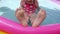 Kids feet dancing on in colorful rainbow inflatable swimming pool. Young girl in pink swimsuit playing in water 4K