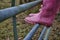 Kids feet in pink wellington boots standing on the field gate.