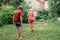 Kids friends splashing with gardening hose sprinkler on backyard on summer day.