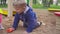 Kids Games. Baby boy digging in the sandbox. Smiles and touches the sand.