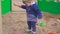 Kids Games. Baby boy digging in the sandbox. Smiles and touches the sand.