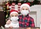 Kids girl and boy in Santa caps in medical masks congratulate each other Merry Christmas and Happy New Year and hug