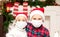 Kids girl and boy in Santa caps in medical masks congratulate each other Merry Christmas and Happy New Year and hug.