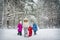 Kids and grandmother running with dog in winter forest