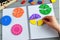 Kids hand moves shapes. Close up of Multicolored math fractions on the open notepad on gray wooden table. Interesting math for kid