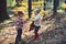 Kids harvest grass in autumn forest. Brother and sister play on fresh air. Small boy and girl friends have fun in woods