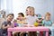 Kids have a dinner in kindergarten. Little boys and girls from the group of children sitting at the table with lunch and