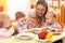 Kids have a lunch in daycare centre. Children eating healthy food in kindergarten. Nursery teacher with babies at table