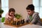 Kids having great time together playing chess. Brother teaching his younger sister playing chess game. Logic development, leisure