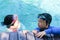 Kids hold on poolside  in swimming suit play and swim in water pool in resort