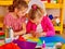 Kids holding colored paper on table in kindergarten .