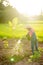 Kids holding tank for watering the tree in organic garden on sun light sky background