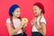 Kids huge fans of baked donuts. Share sweet donut. Girls in beret hats hold glazed donut red background. Kids playful