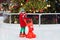 Kids ice skating in winter park rink. Children ice skate on Christmas fair. Little boy with skates on cold day. Snow outdoor fun