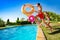 Kids with inflatable buoys jump dive into pool