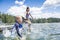 Kids jumping off the dock into a beautiful mountain lake. Having fun on a summer vacation