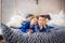 Kids laying in bed with gray cover in white bedroom. Little boy and girl, brother and sister, siblings play on the bed wearing