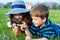 Kids looking to dandelion with a magnifying glass