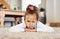 Kids love being silly. Portrait of an adorable little girl making a face while lying on the floor at home.