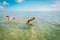 Kids making handstand in sea, boy and girl divinig on beach