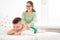 Kids massage concept background. Young female massage therapist giving a 6 year old boy back massage. Physical therapy.