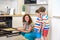 Kids and mother baking. Two children and parent cooking. Little boy and brother boy cook and bake in a white kitchen with modern