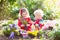 Kids plant and water flowers in spring garden