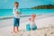 Kids play with globe and toy plane on beach, travel concept