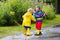 Kids play in rain and puddle in autumn