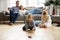 Kids playing on floor, parents relaxing on sofa at home