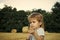 Kids playing - happy game. Small kid with spikelet at hay bale, summer